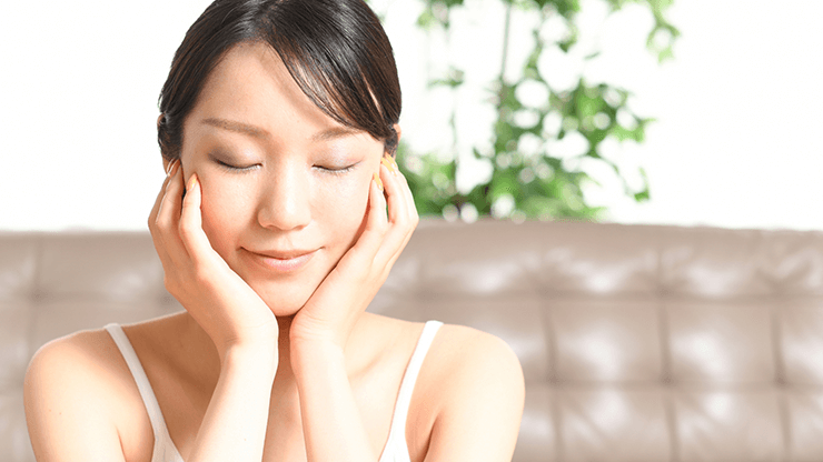 顔に手を当てて目を閉じた女性の画像