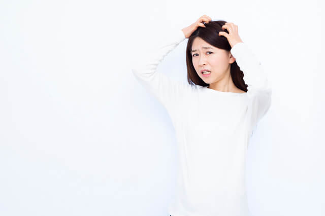 頭をかゆがる女性