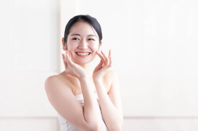 顔に手を当てて笑う女性の画像