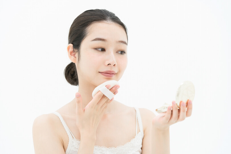 コンパクトでファンデーションをする女性