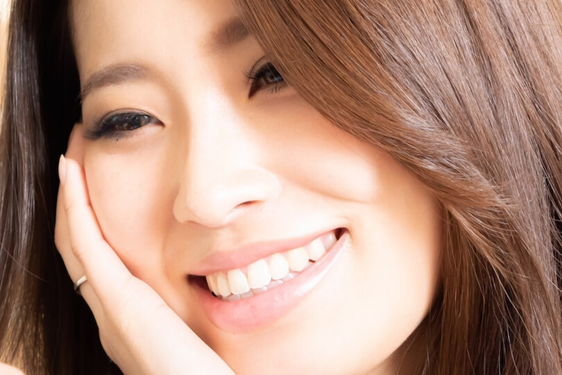 顔に手を当てて笑う女性の画像