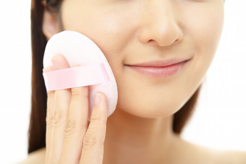 ファンデーションパフを顔に当てる女性の画像