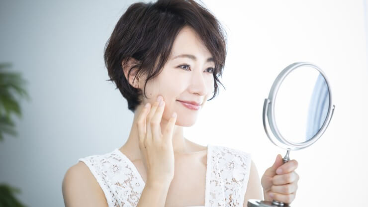 鏡を見て微笑む女性の画像