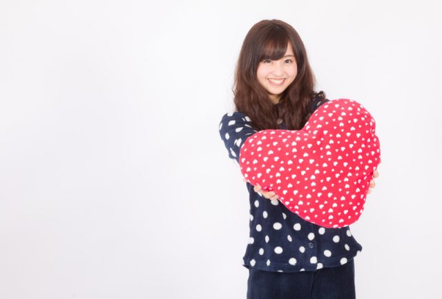 ハートのクッションを差し出す女性